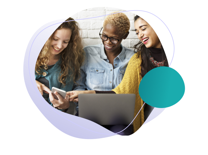 Three smiling young women working on a laptop, a cell phone and a tablet.