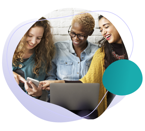 Three smiling young women working on a laptop, a mobile phone and a tablet.